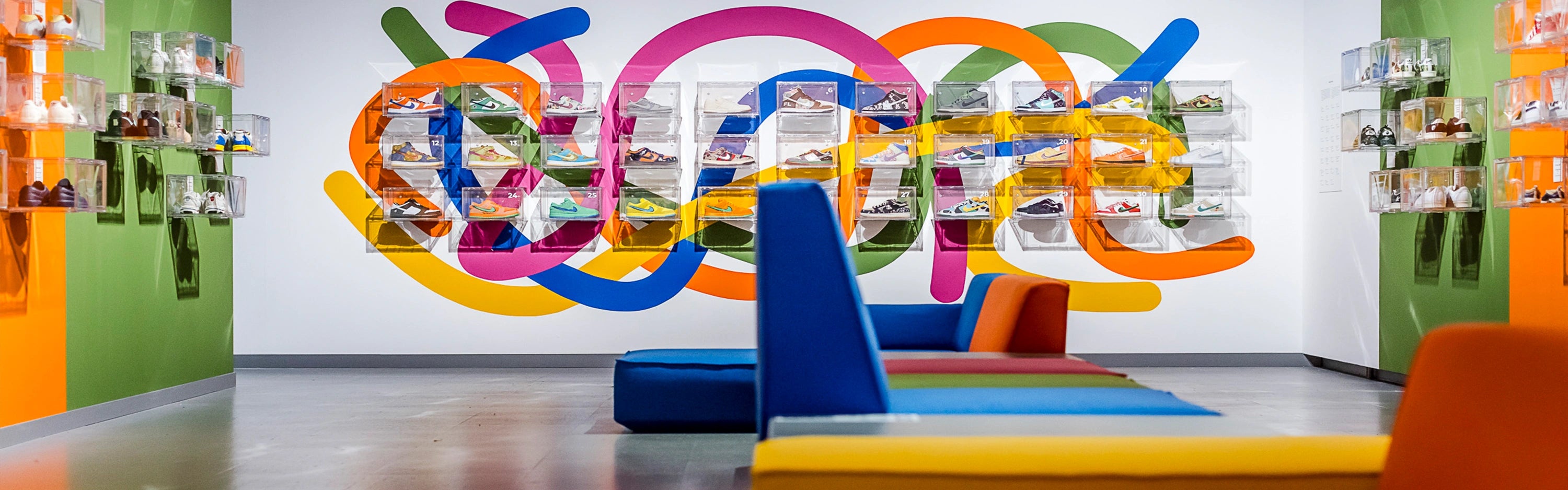 Farbige Sitzmodule im Ausstellungsraum mit Sneakers an der Wand – Gestaltung mit modernen Contract Möbeln