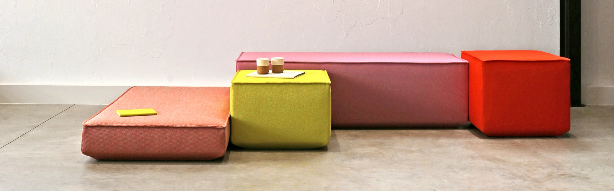 Farbige Polstermodule in Orange, Pink, Rot und Limettengrün als flexible Sitzmöbel in einem modernen Büro- oder Loungebereich