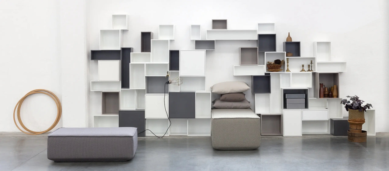 Modulares Regalsystem in Grau und Weiß mit grauen Sofamodulen und Kissen.