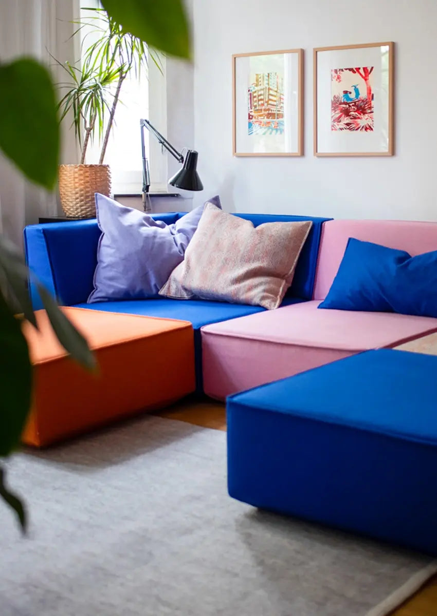 Nahaufnahme bunte modulare Sofapolster in Blau, Orange und Rosa mit Kissen.