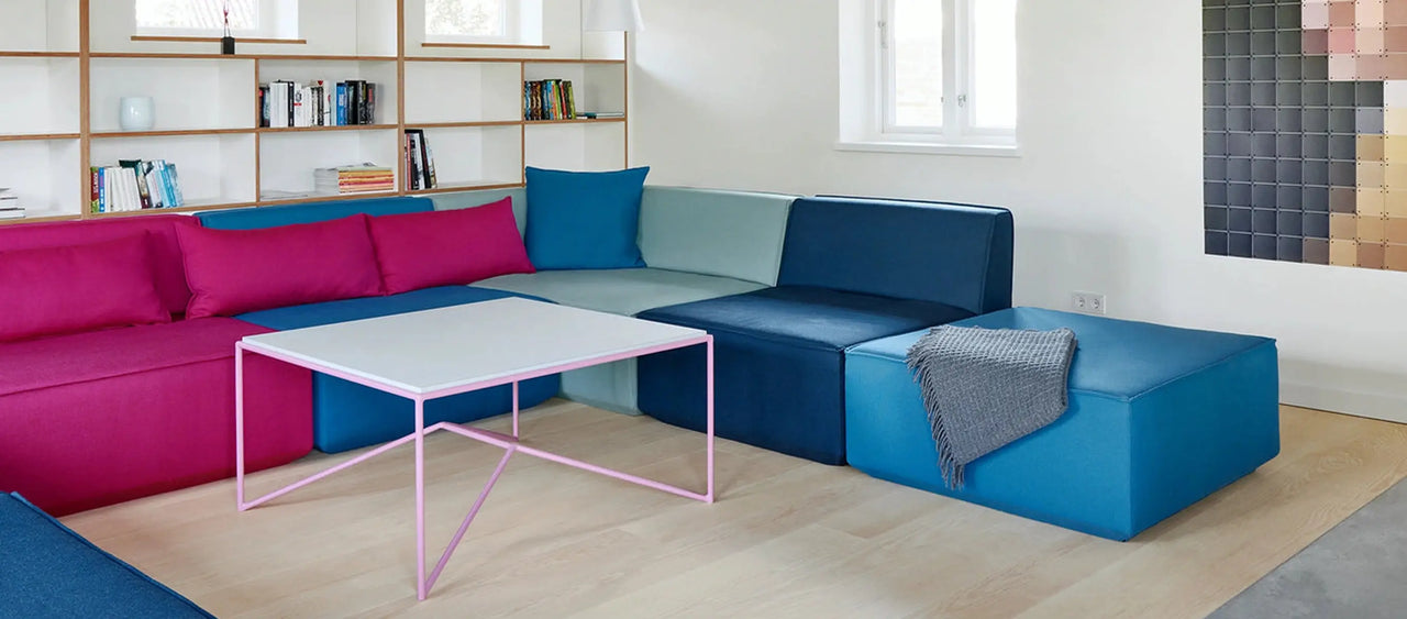 Modulares Sofa in Pink und Blau mit Holzregal und rosa Couchtisch im Altbau-Wohnzimmer.