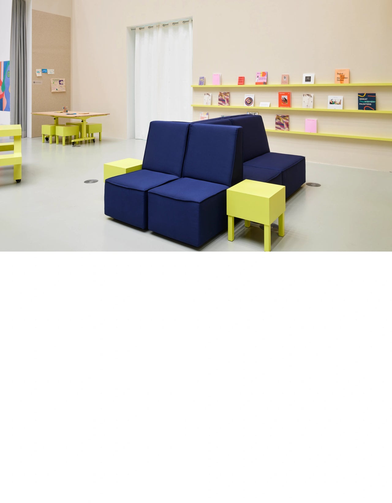 Farbige Sitzgruppe mit modularen blauen Polstermodulen und gelben Beistelltischen in einem modernen Museumsraum mit Ausstellungselementen