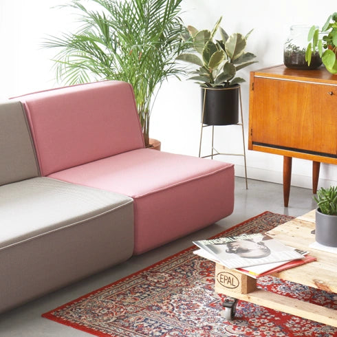 2 seater sofa in grey and pink, combined with wooden furniture and plants in a cosy living room.