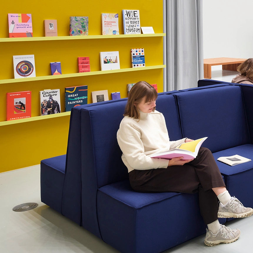 Éléments de canapé modulaires dans une salle de formation et d'exposition moderne avec un mur jaune.