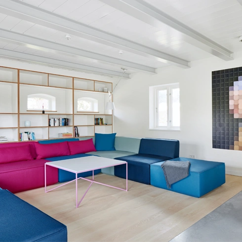 Canapé d'angle en bleu et rose, combiné avec des meubles en bois clair et un aménagement moderne de l'espace de vie.