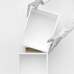 Deux mains positionnent un module d'étagère Cubit blanc sur un autre - scène minimaliste avec logo