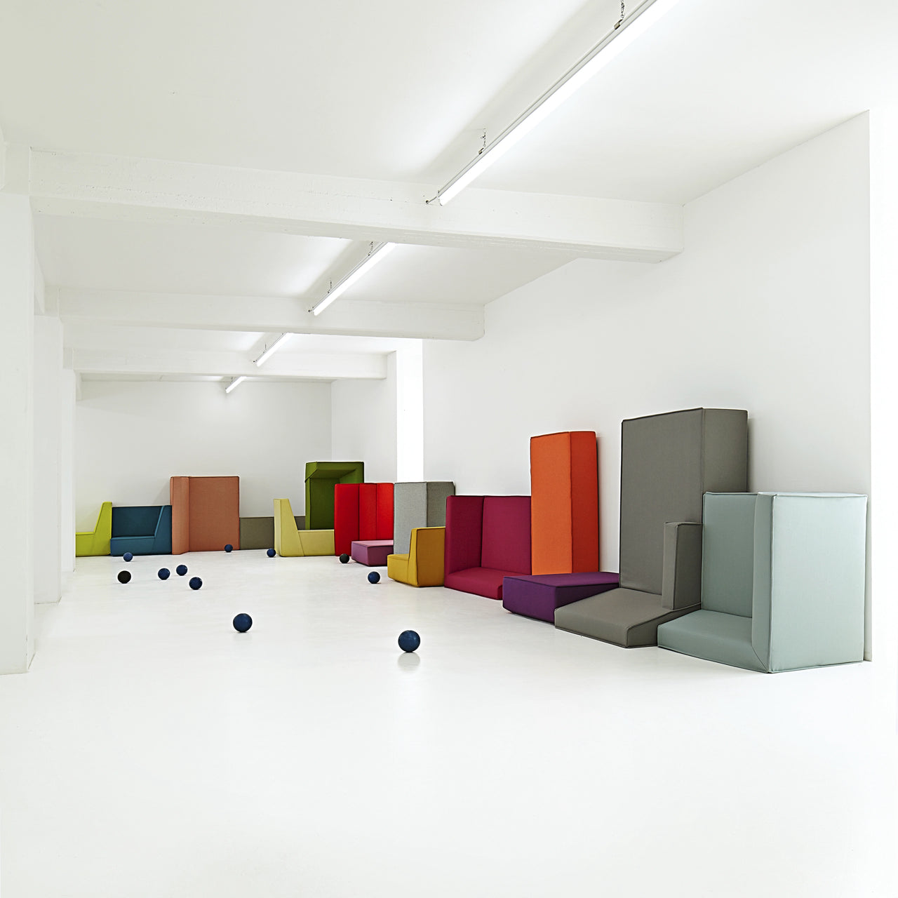 canapé modulable en plusieurs parties aux couleurs vives, disposé librement dans une pièce blanche