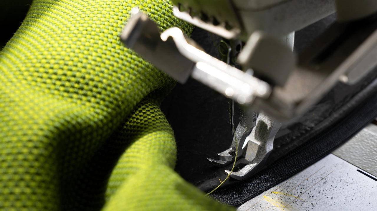 Gros plan sur une machine à coudre travaillant un tissu d'ameublement vert vif - focus sur l'aiguille, la texture du tissu et le savoir-faire artisanal